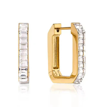 A pair of gold huggie hoop earrings with clear rectangular baguette-cut gemstones set along the front edges, shown on a clean white background with a subtle reflection.