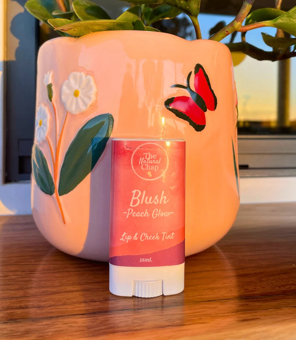 Lip and cheek tint stick with decorative pink container on a wooden surface