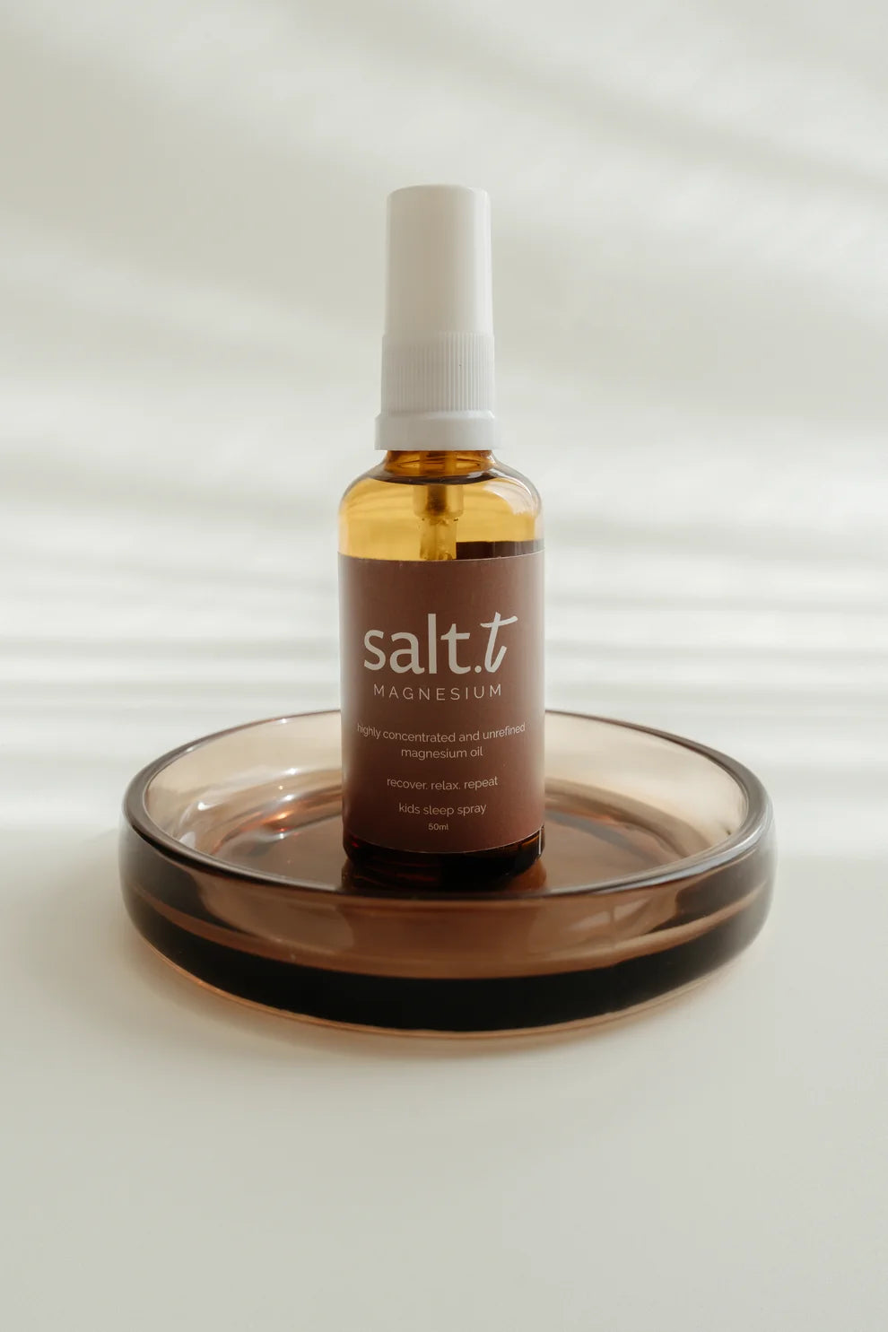 Bottle of salt t magnesium on a glass coaster with a white background