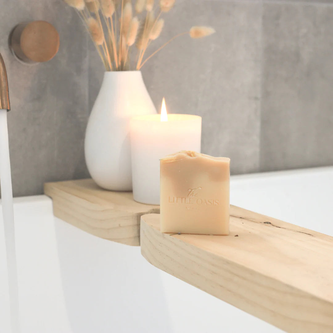 Candle and soap on a wooden shelf with a vase in the background