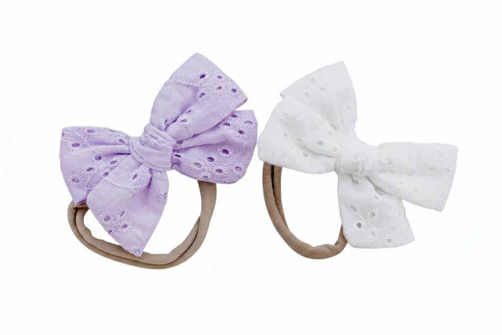 Two bow hairbands, one purple and one white, on a white background.