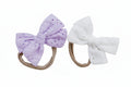 Two bow hairbands, one purple and one white, on a white background.