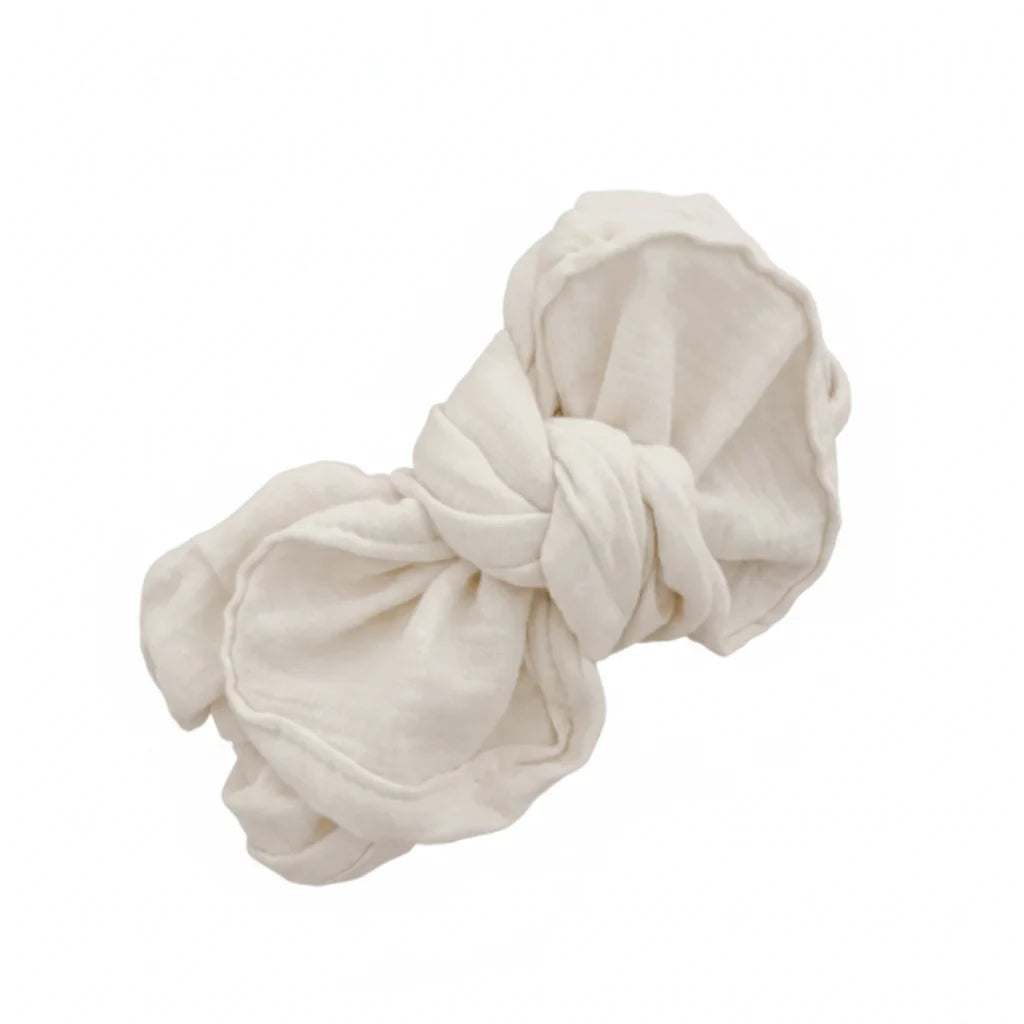An off-white cotton muslin fabric scrunchie, knotted and displayed on a solid white background.