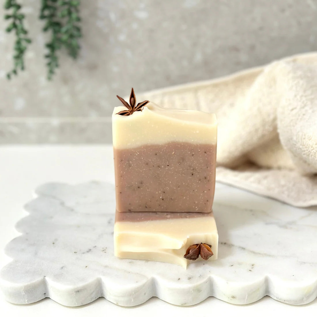 Two stacked soap bars with star anise on a marble surface